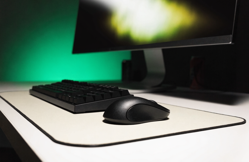 Clean modern gaming desk at night with mechanical keyboard and soft green ambient light