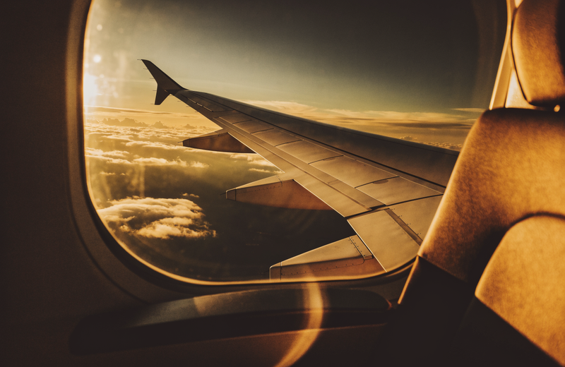 View from an airplane window seat over golden sunset clouds