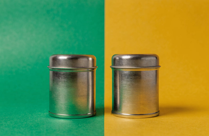 Two supplement tins side by side on a split green + goldenrod backdrop