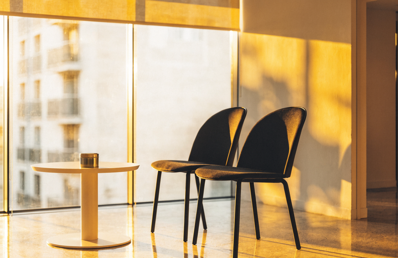 Two empty chairs in a bright office waiting area in warm golden light before an interview