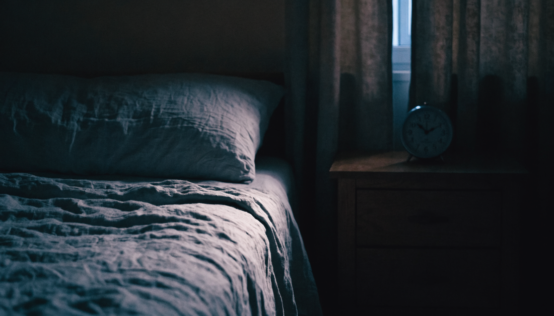 A dark bedroom in the small hours, rumpled sheets and a clock on the nightstand lit by faint moonlight