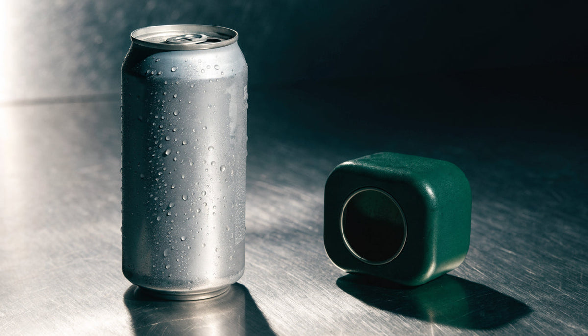Energy drink can beside a caffeine pouch tin in a comparison still life