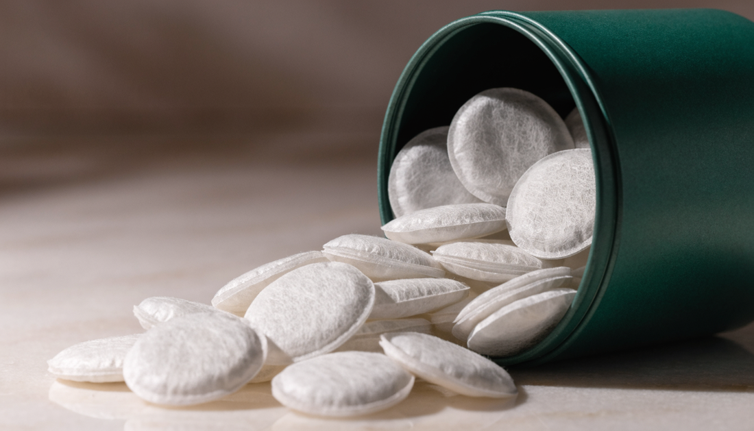 Caffeine pouches spilling from an open tin onto a stone surface