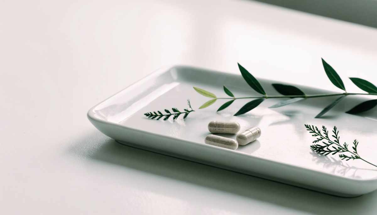 Capsules and green botanicals on a white tray, over-the-counter focus supplements