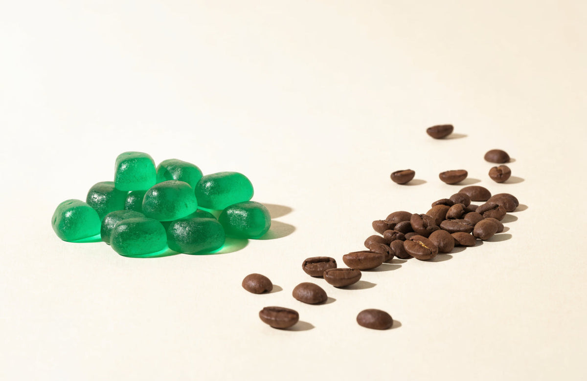 Green caffeine gummies beside roasted coffee beans on a cream background