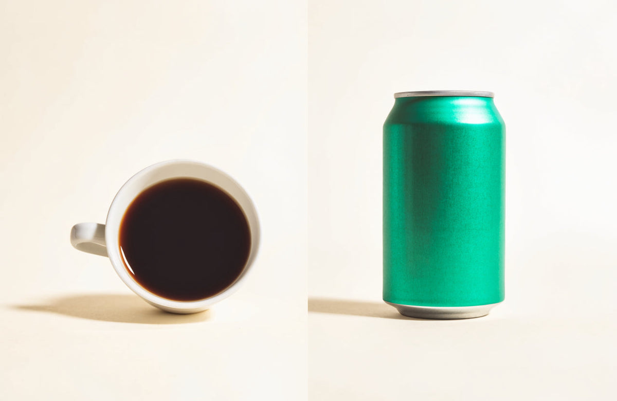 A cup of black coffee facing an unbranded green energy drink can on a cream background