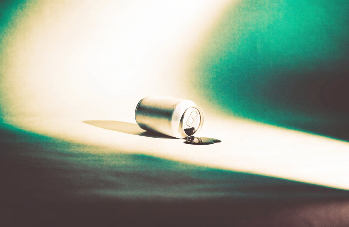 An unbranded aluminum can tipped over with a long shadow, conveying the energy drink crash