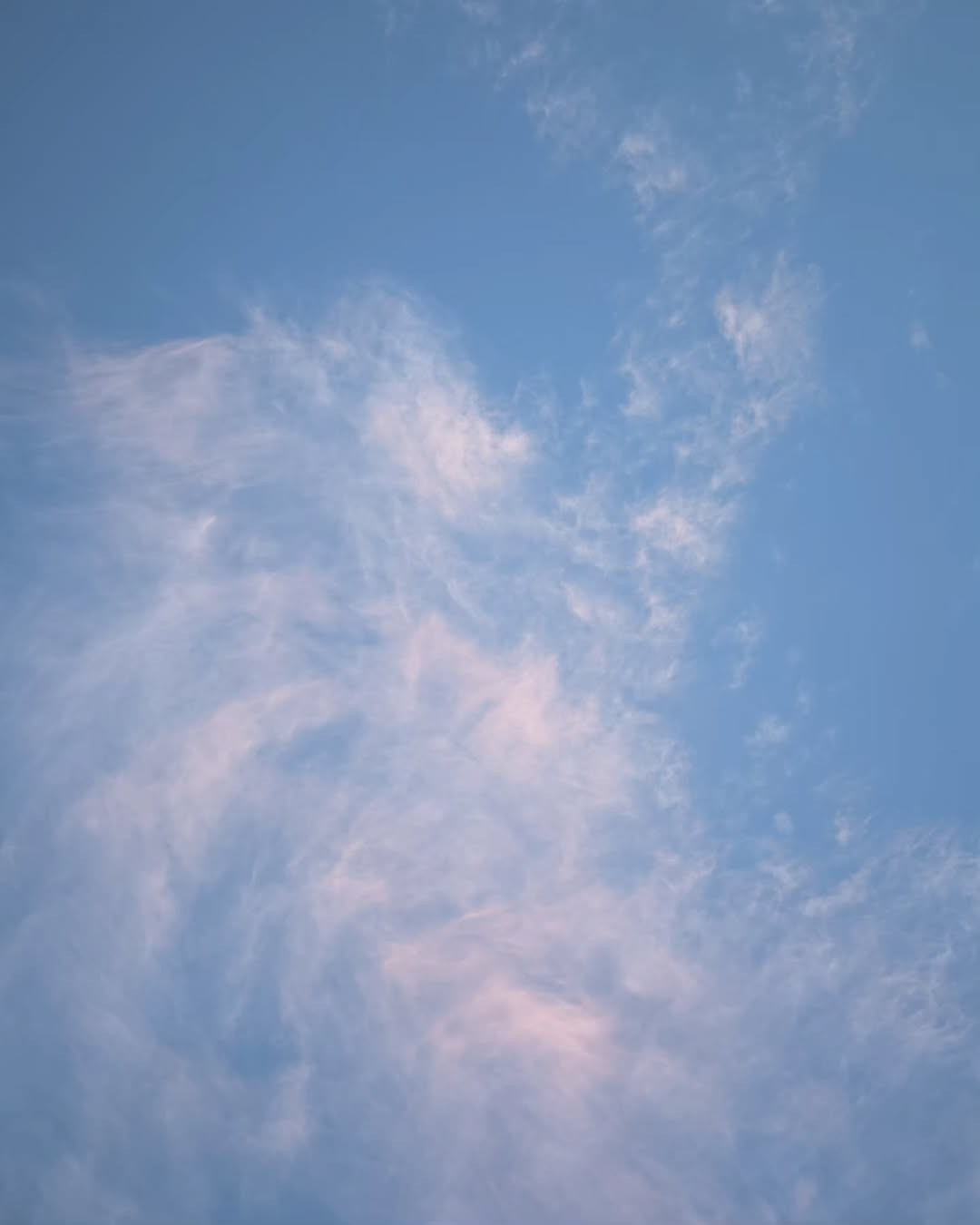 Light pink clouds against a blue sky