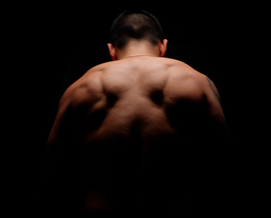 Man with a muscular back against a black background